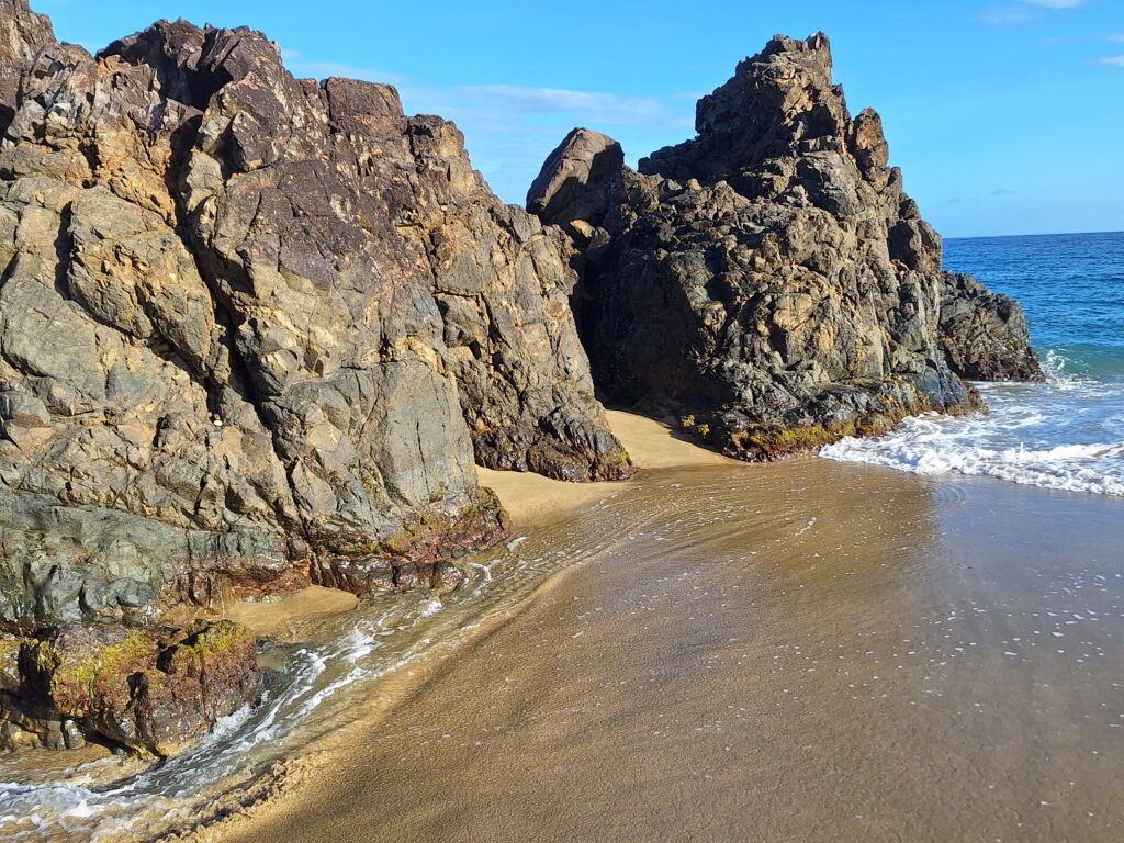 Rock formations beside a sandy beach and ocean