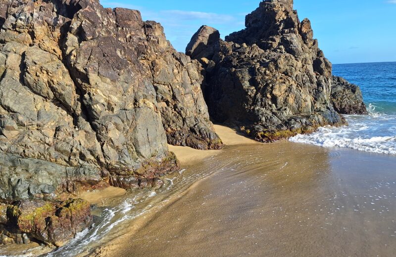 Rock formations beside a sandy beach and ocean